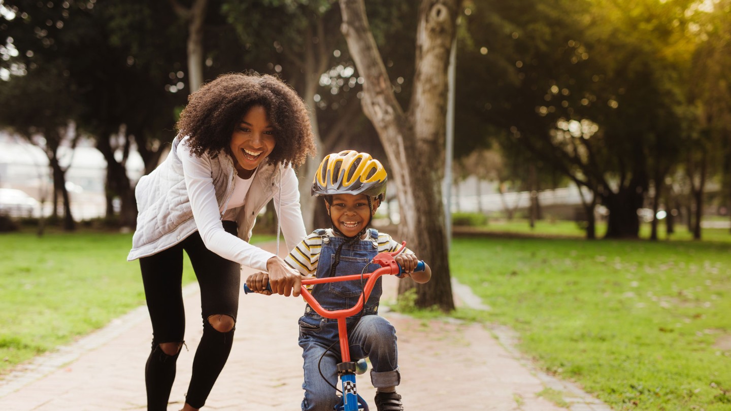 Mom helping young son ride bike