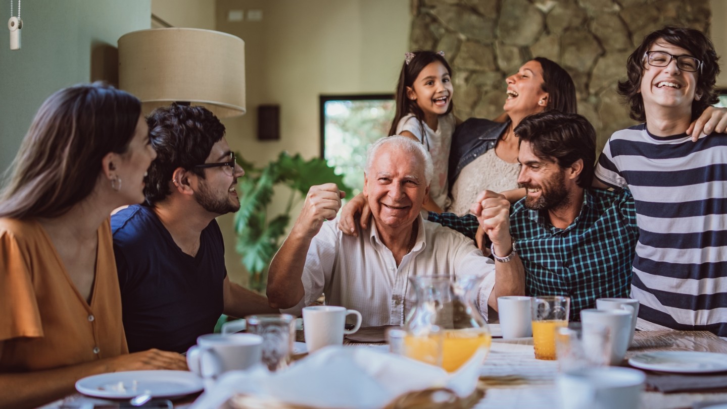 family at breakfast table smiling with grandpa