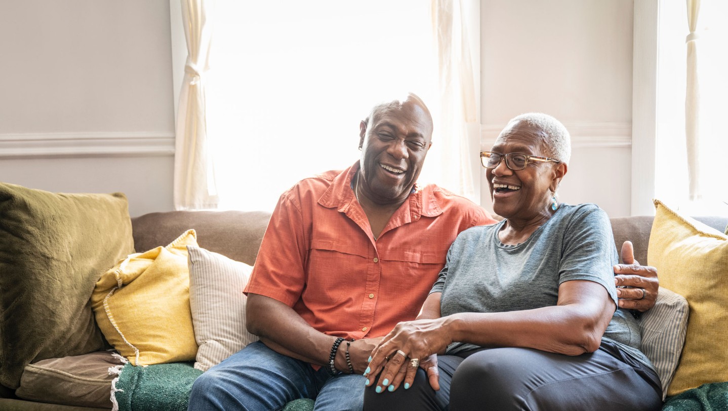 Older couple sitting on couch smiling