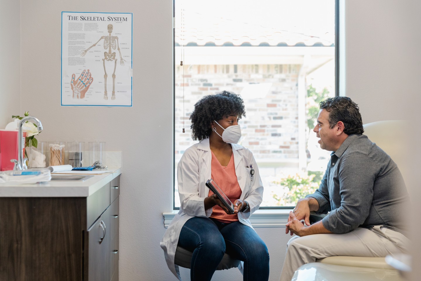 Male patient in the doctors office talking with female doctor